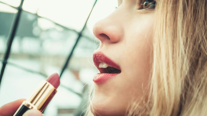 selective focus photography of woman holding lipstick